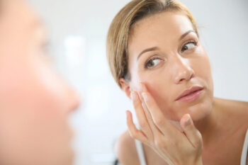 Woman applying skincare in mirror