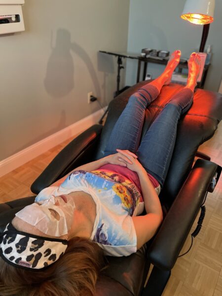 Person reclining with sheet mask under lamp