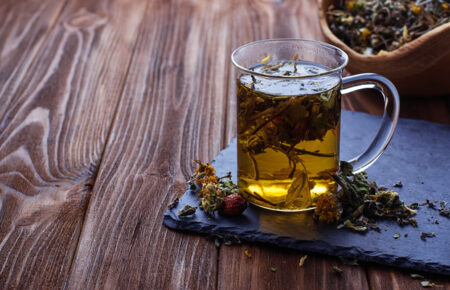Glass mug of herbal tea with loose herbs